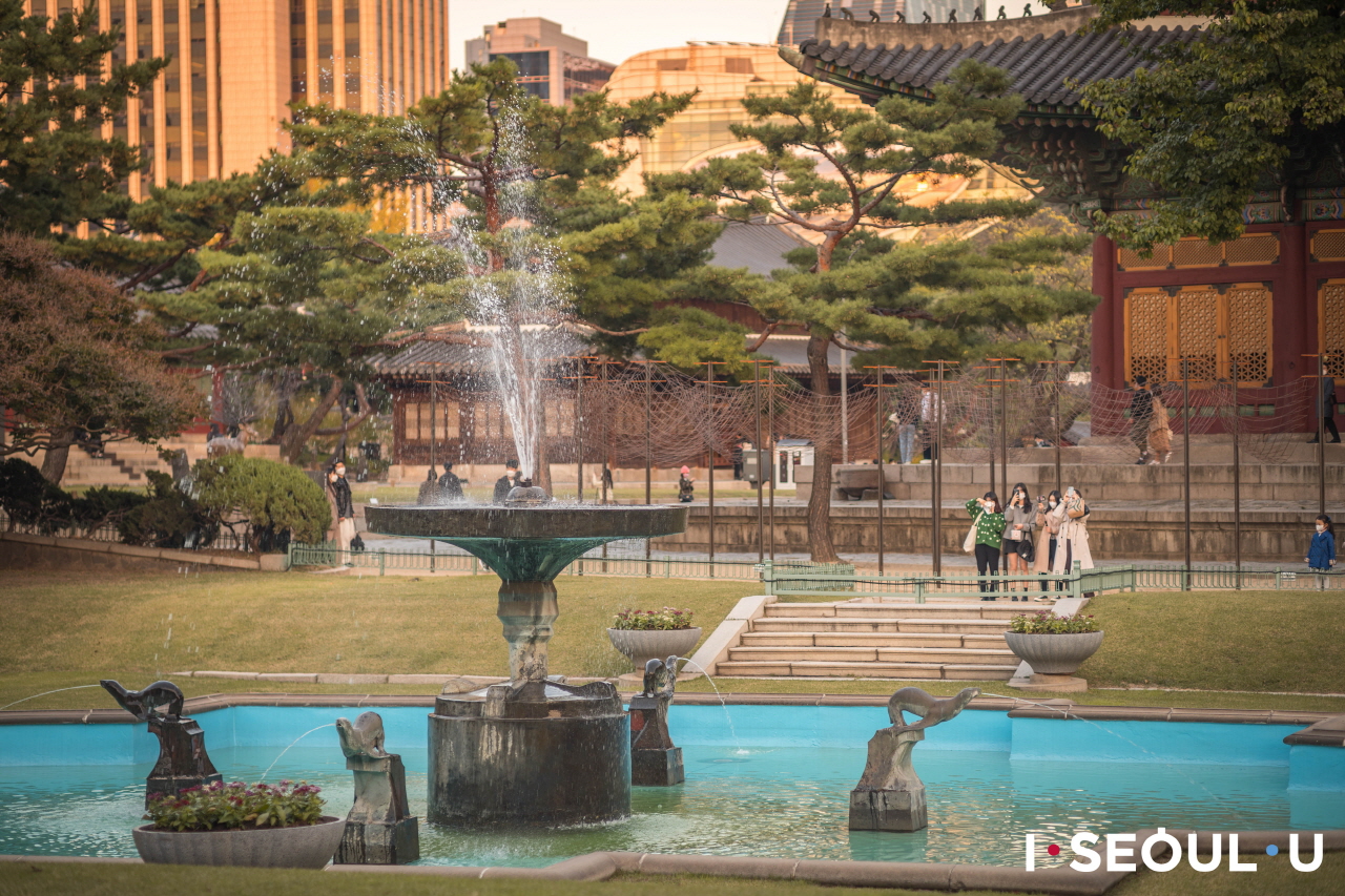 观看德寿宫旁晚霞笼罩的喷泉的人们