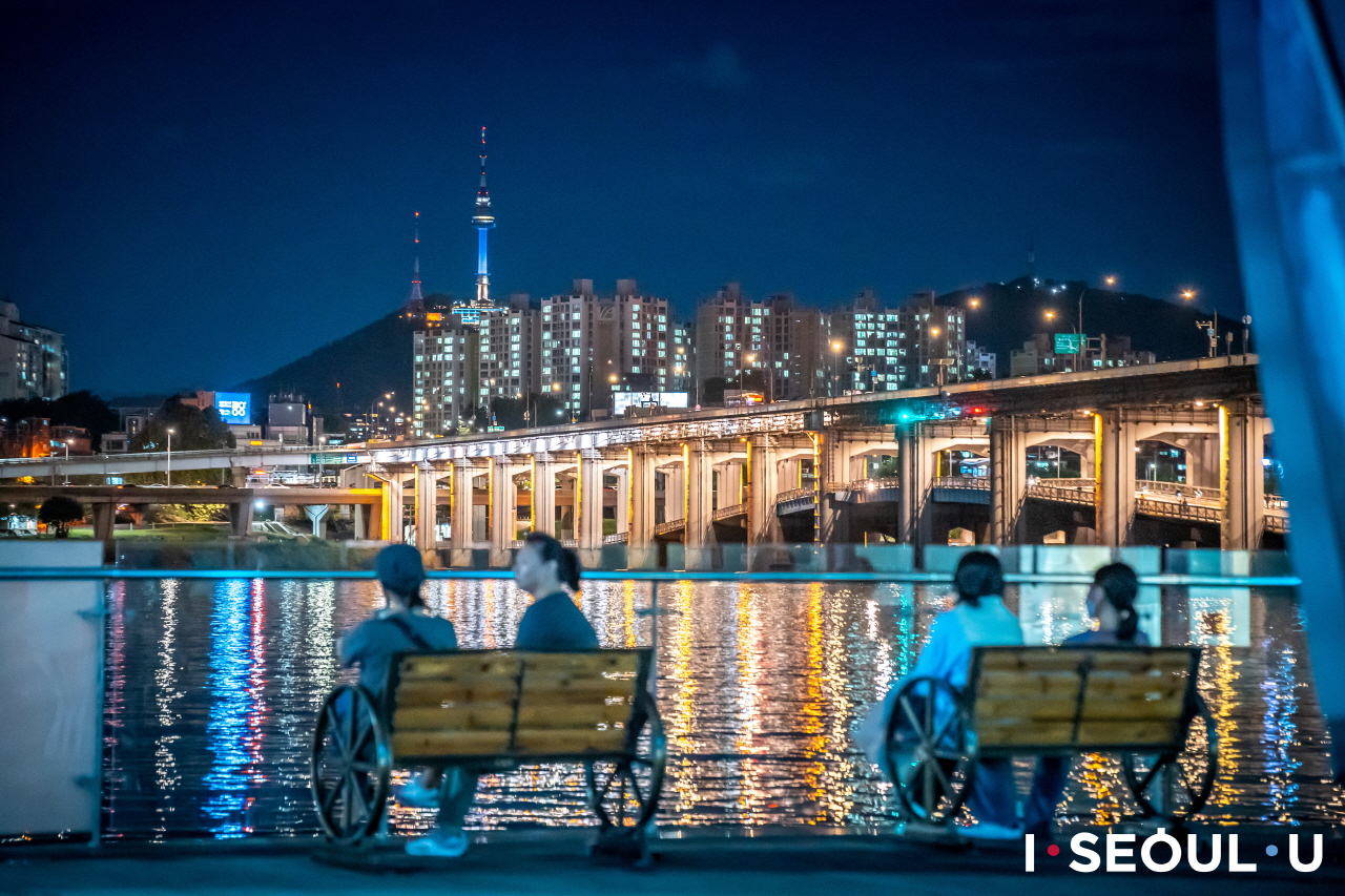 坐在三光岛长椅上观赏汉江夜景的人们