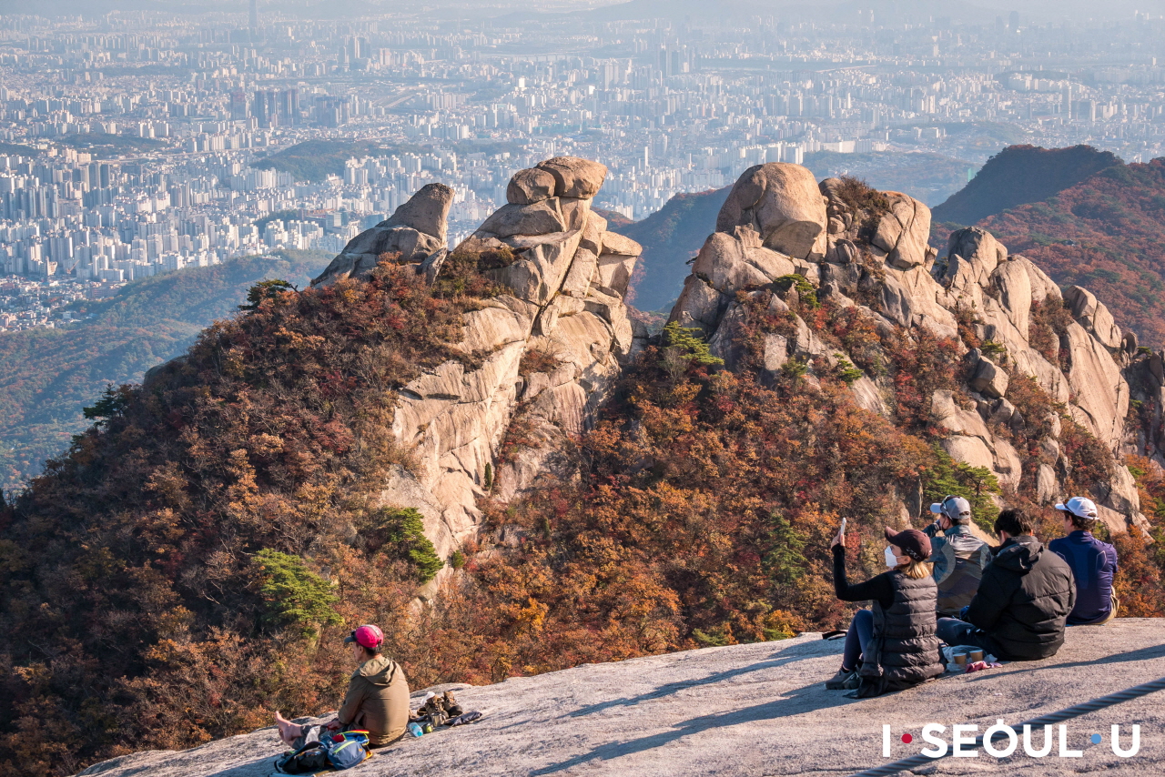 坐在北汉山山顶俯瞰首尔市区城景的人们