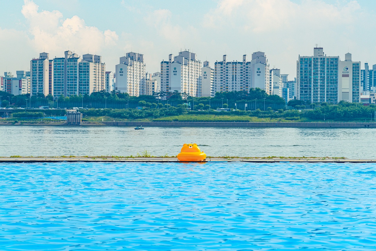 以小区为背景，漂浮着黄色游泳圈的兰芝汉江公园水上乐园的照片。